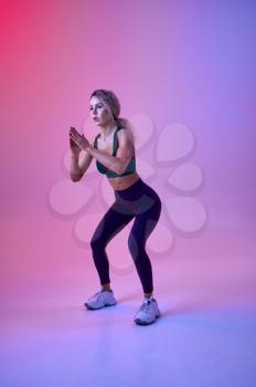 Slim female athlete doing exercise in studio, neon background. Fitness sportswoman at the photo shoot, sport concept, active lifestyle motivation