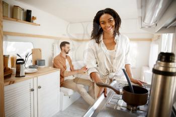 Woman cooking in rv kitchen, camping in a trailer. Man and woman travels on van, romantic vacations on motorhome, campers leisures in camping-car