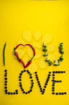 Berries love word isolated on yellow background, top view. Organic vegetarian food, grocery assortment, natural eco products, healthy lifestyle concept