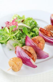 Bacon and potato skewer with mixed salad greens