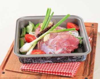Raw pork and fresh vegetables in a baking pan