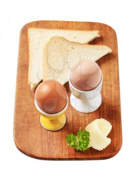 Boiled eggs in eggcups and slices of white bread