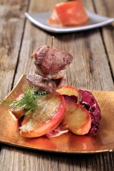 Roasted meat on stick and slices of apple