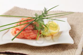 Closeup of salmon tartare garnished with chives and dill