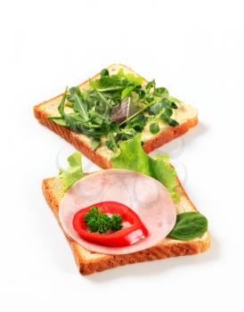 Slices of white bread with ham and salad greens