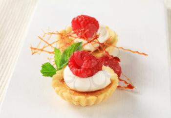 Creme brulee tartlets topped with cream and raspberry