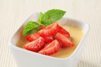 Small dish of vanilla pudding topped with strawberries