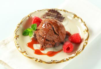 Scoop of chocolate brownie ice cream with toffee sauce and raspberries