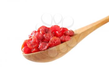 Dried red cherries on wooden spoon
