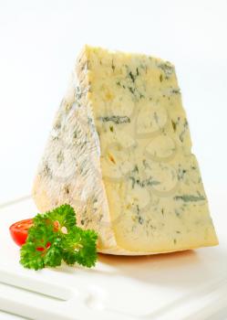 Large wedge of blue cheese on a cutting board