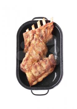 Oven-roasted rack of pork ribs in a baking tray - cut out on white