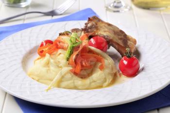 Roast pork ribs and mashed potato garnished with vegetables