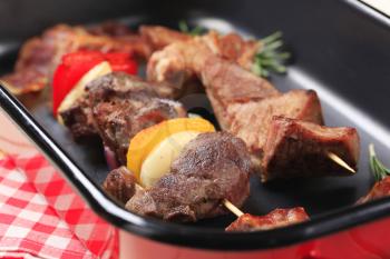Shish kebabs and rashers of bacon in a roasting pan