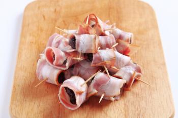 Bacon wrapped prunes on a cutting board