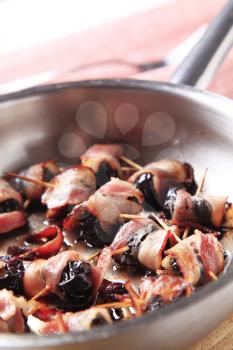 Bacon wrapped prunes being pan roasted - detail
