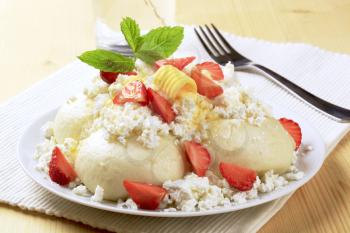 Fruit dumplings served with cottage cheese, sugar, butter and strawberries