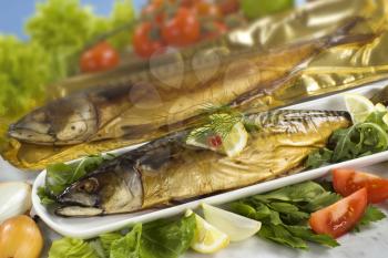 Closeup of two smoked mackerel and fresh vegetables
