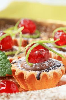 Chocolate filled tartlets topped with glace cherries