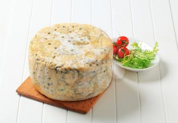 Wheel of blue cheese on cutting board