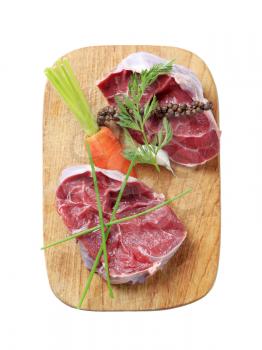 Raw shin beef, vegetable and herbs  on a cutting board