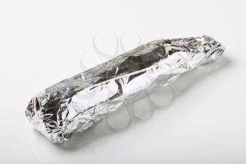Raw pork tenderloin wrapped in aluminum foil