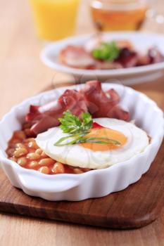 English breakfast of baked beans, sausages, fried egg and bacon