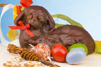 Still life of Easter lamb with chocolate icing, painted eggs and whipping cane