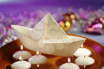 Floating Candles and Paper Boat in Bowl of Water
