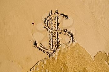 Sea washing off a dollar sign drawn in the sand 