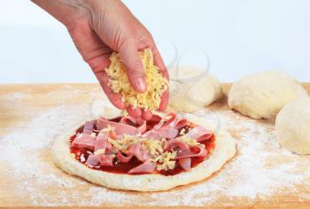 Cook sprinkling shredded cheese over pizza