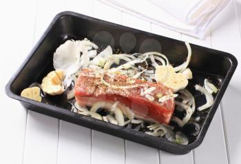 Pork belly with garlic and onion in a baking tray