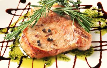Pan-roasted pork chop decorated with rosemary and balsamico