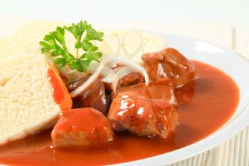 Pork meat in tomato sauce served with bread dumplings