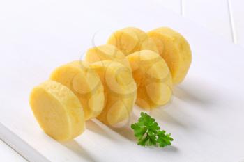 Sliced potato dumplings arranged on a white cutting board