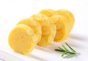 Sliced potato dumplings arranged on a white cutting board