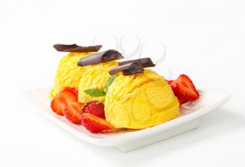 Three scoops of ice cream garnished with chocolate curls and strawberries