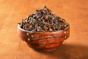 Heap of dried cloves in wooden bowl