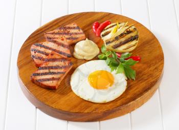 Grilled meatloaf with sunny side up fried egg and mustard