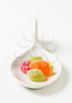 Fruit-shaped gummy candy on ceramic spoon
