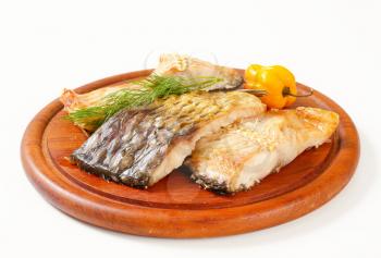 Oven-baked carp fillets on round cutting board