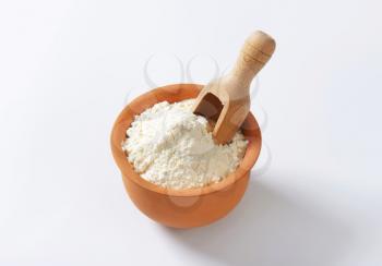 Finely ground flour and wooden scoop in terracotta bowl