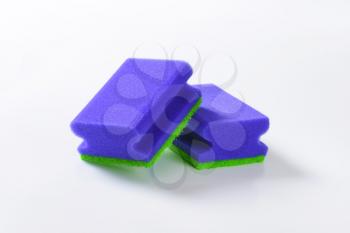 two blue kitchen sponges on white background