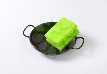 green kitchen sponge on black skillet
