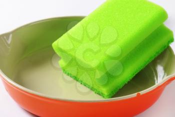green kitchen sponge on ceramic baking dish