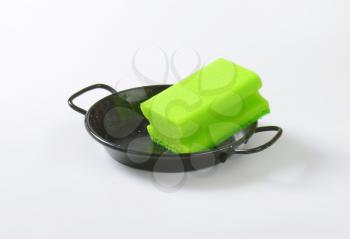 green kitchen sponge on black skillet
