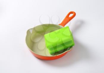 green kitchen sponge on ceramic pan