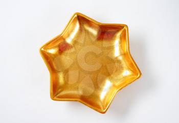 empty star shaped gold bowl on off-white background