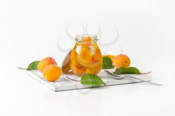 Jar of apricot compote and bowl of fresh apricots