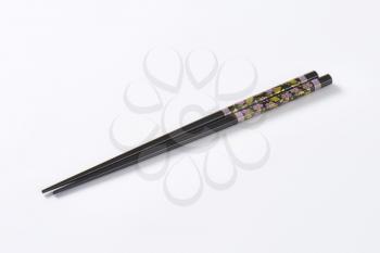 A pair of black chopsticks with floral pattern