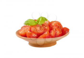 Halved red cherry tomatoes in terracotta bowl